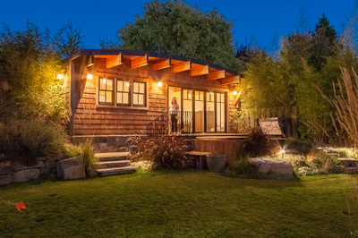 A wood shingle-clad accessory dwelling unit with a vaulted roof supported by large wood beams.
