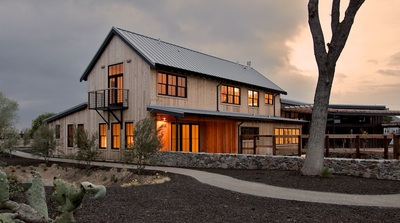 An early evening view of a modern farmhouse-style home with vertical cedar siding.